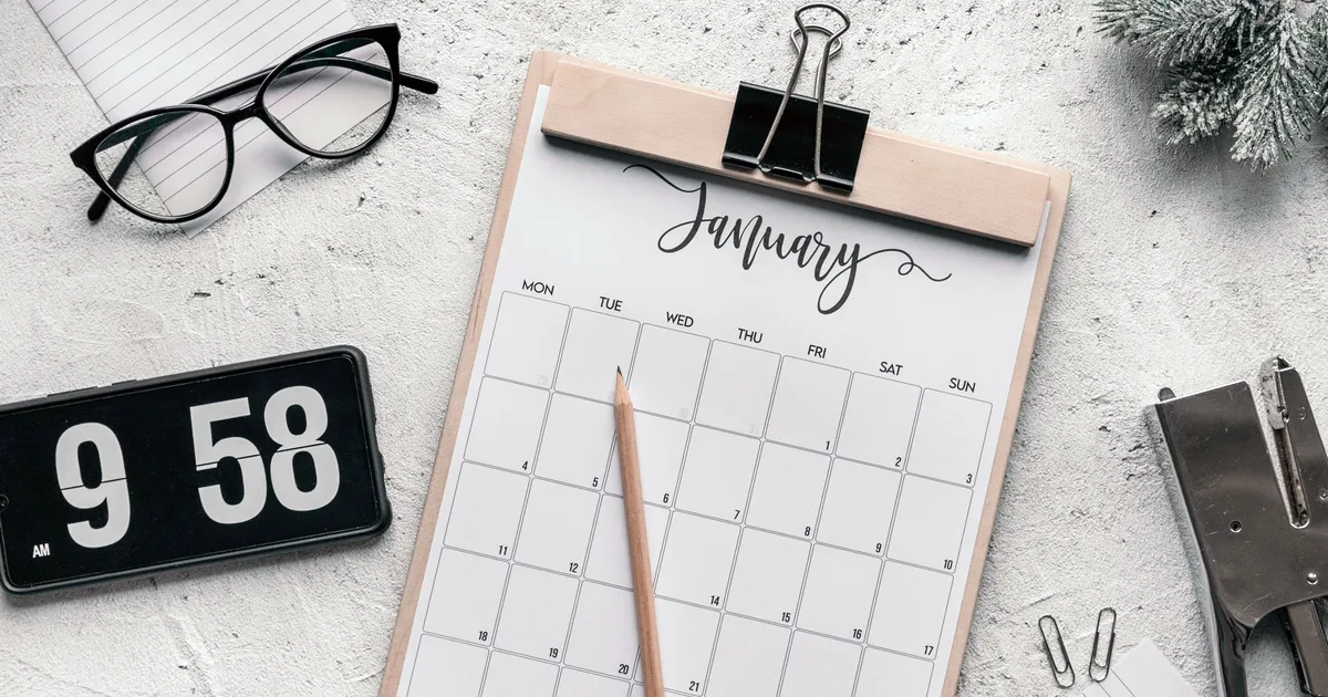 A calendar, clock, and pencil arranged on a planning desk