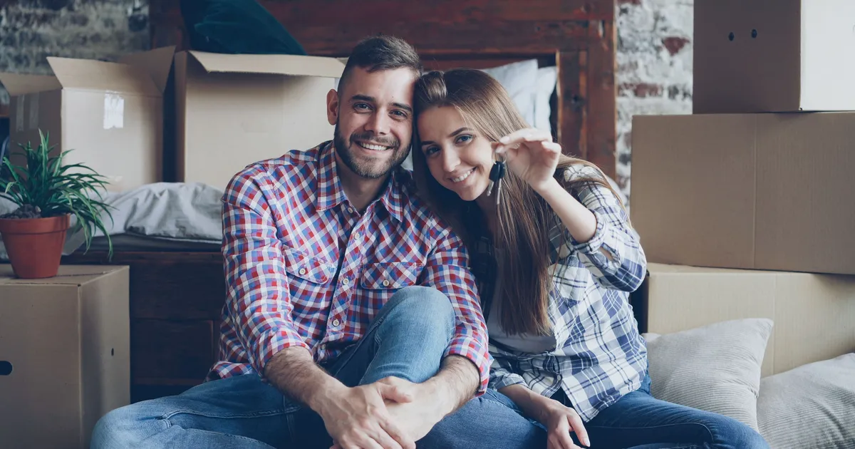 A couple with house keys surrounded by moving boxes